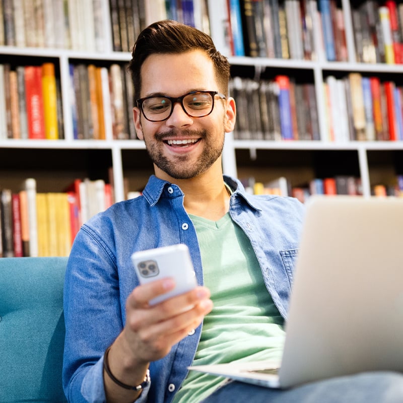 young-man-on-laptop-looking-at-phone