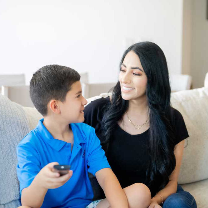 Kid and mom smiling and watching tv