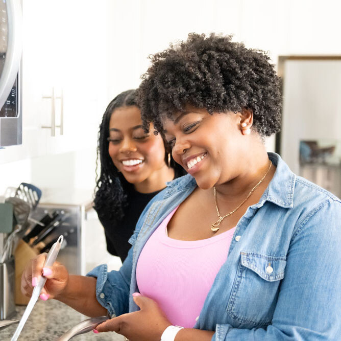 Teen and mom smiling while doing dishes